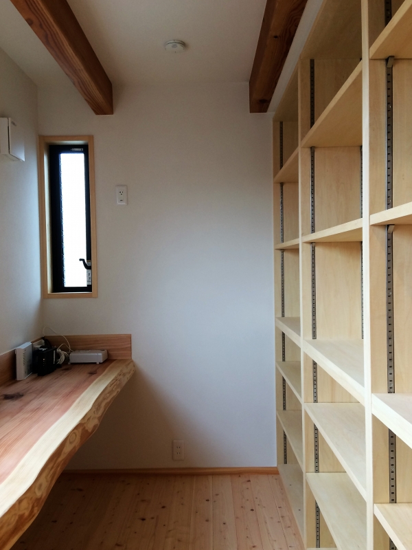 造り付けで作成した本棚と無垢のカウンター机がある書斎室