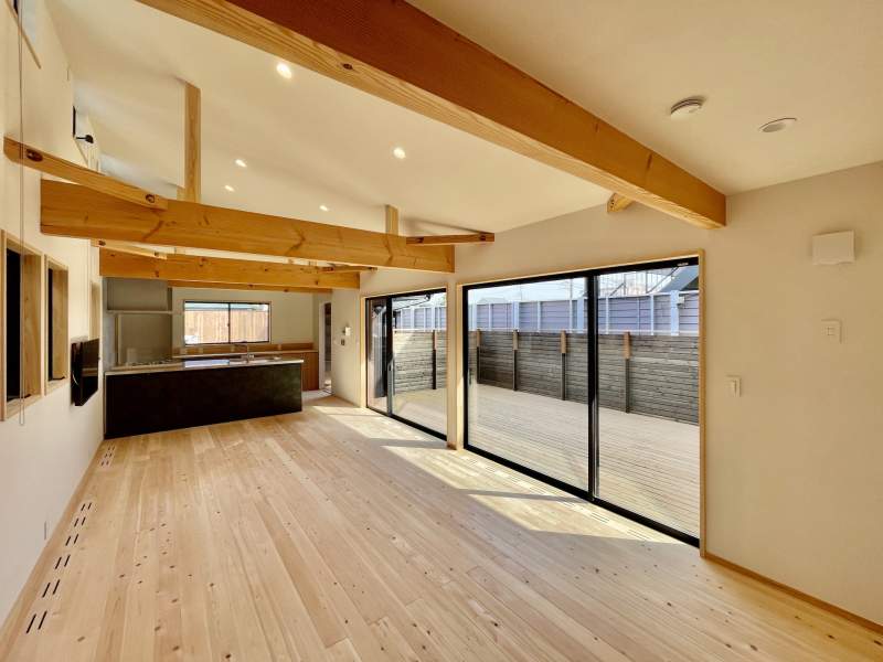 木の塀で目隠しされた広いウッドデッキの中庭に隣接した吹抜けのリビング