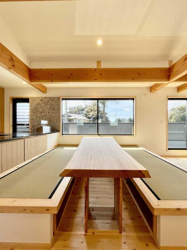 畳ベンチと無垢1枚ものの造作テーブルがある吹抜けのダイニングスペース